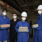 Four people posing for camera, three of the four holding blocks.